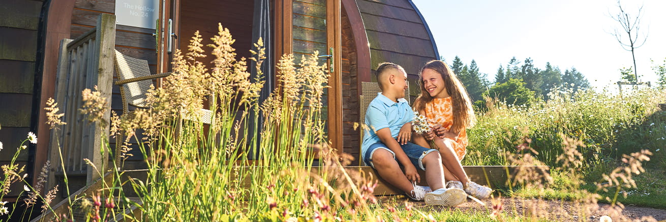 Two children sitting outside a Whitemead Forest Park glamping pod